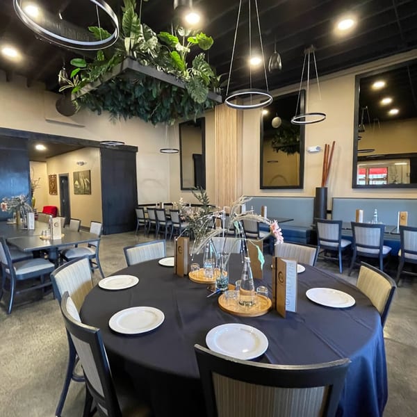 ZEN Kitchen & Bar's dining room with round tables, modern lighting, and lush ceiling greenery.