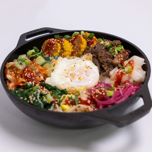 ZEN Kitchen & Bar's colorful bibimbap with beef, corn, kimchi, and a fried egg in a black bowl.