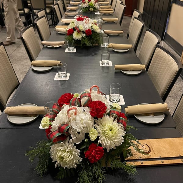 Long dining table set for a holiday event at ZEN Kitchen & Bar, with festive floral centerpieces.